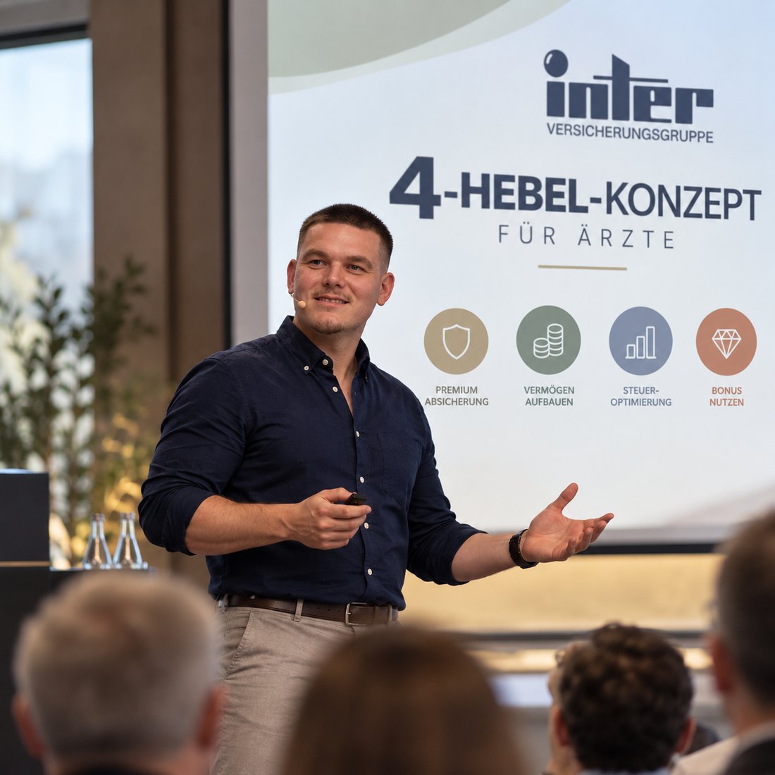 Marius Schneider erklärt das 4-Hebel-Konzept für Ärzte vor Publikum. Auf der Leinwand die vier Hebel: Premium-Absicherung, Vermögen aufbauen, Altersrückstellungen aufbauen, Steueroptimierung und Arbeitgeberzuschuss.